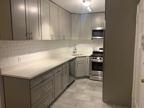 A kitchen with white cabinets and a white countertop.
