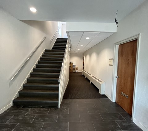 A hallway with a staircase and a door.