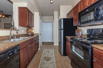 a kitchen with black appliances and brown cabinets at The Preserve by Picerne, N Las Vegas