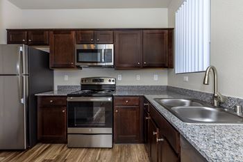 a kitchen with granite counter tops and stainless steel appliances at The Covington by Picerne, Nevada
