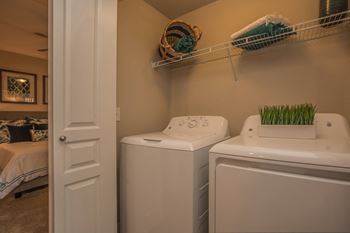 a laundry room with a washer and dryer and a door to a bedroom