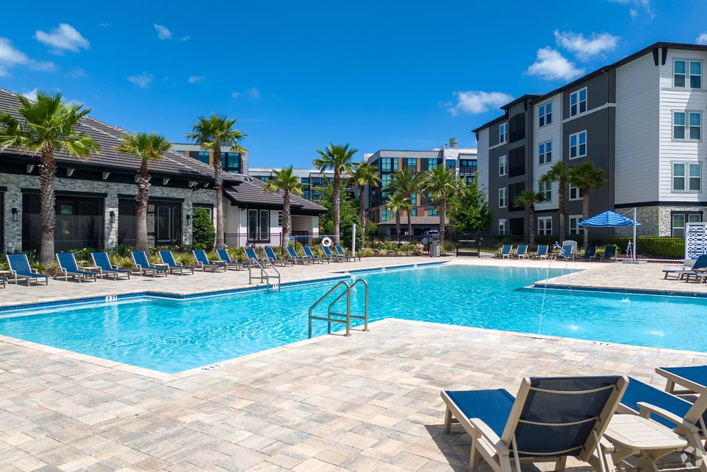 A swimming pool surrounded by lounge chairs and palm trees.