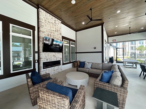 A modern outdoor living room with a stone fireplace and wicker furniture.