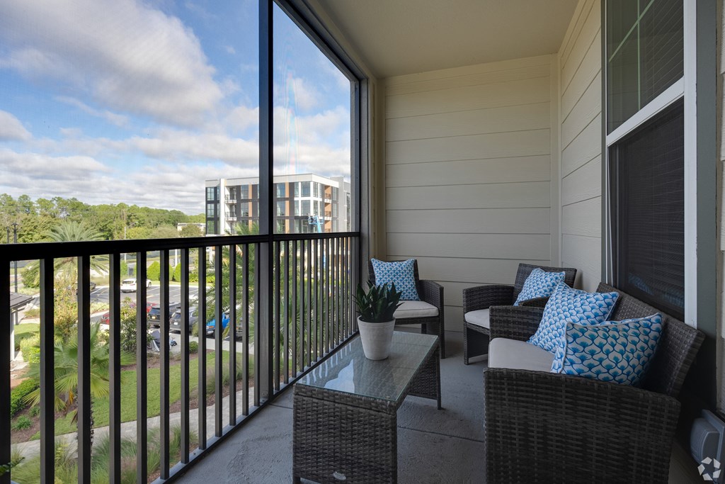 A balcony with a table and chairs overlooking a parking lot.