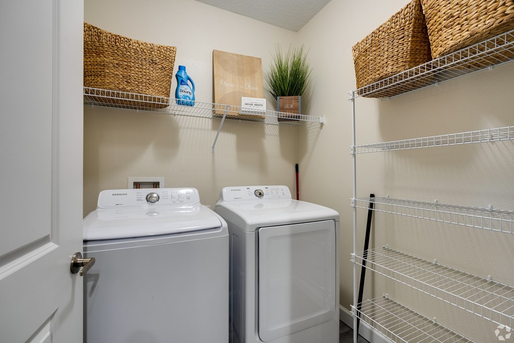 A laundry room with two washing machines and a basket on the wall.