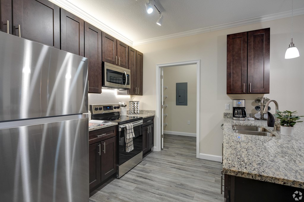 A kitchen with a stainless steel refrigerator and dark wood cabinets.