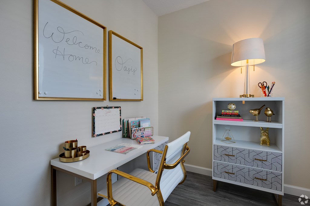 A white desk with a gold chair and a lamp on a shelf.