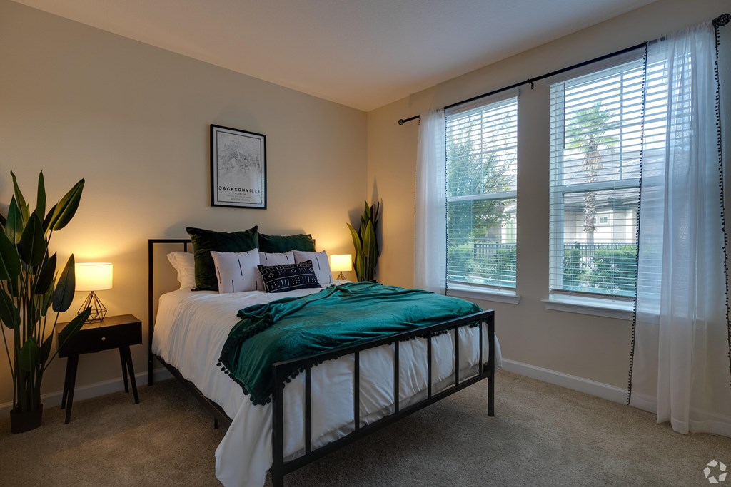 A bedroom with a bed, nightstands, and a window with blinds.