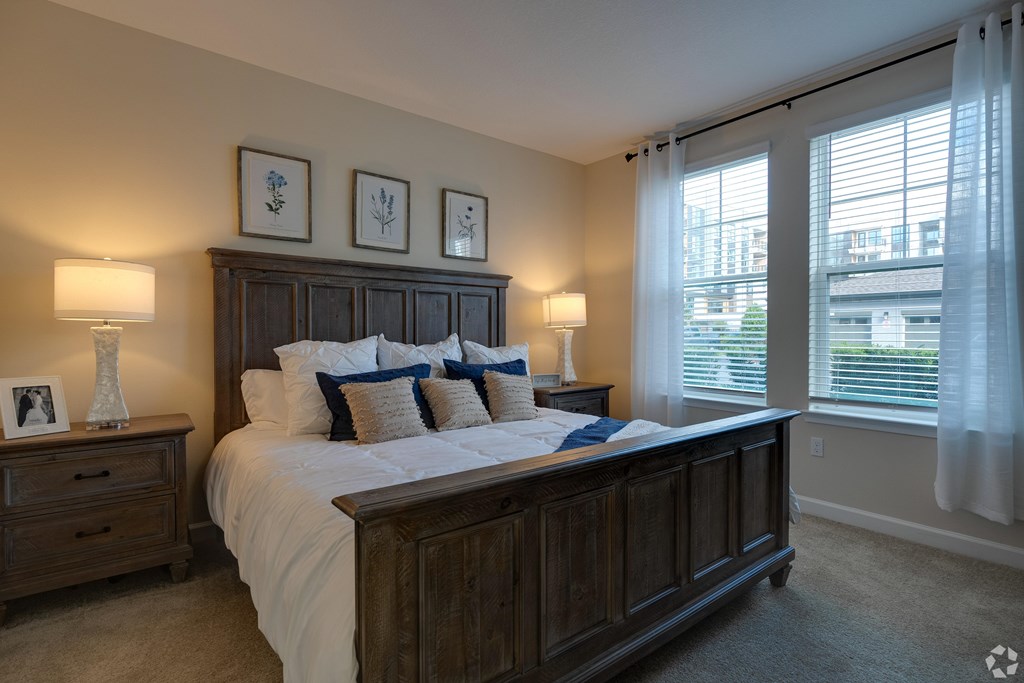 A bedroom with a large bed, two lamps, and pictures on the wall.