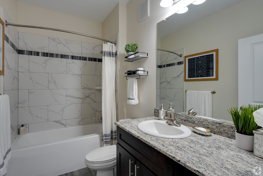 A bathroom with a marble countertop and a white bathtub.