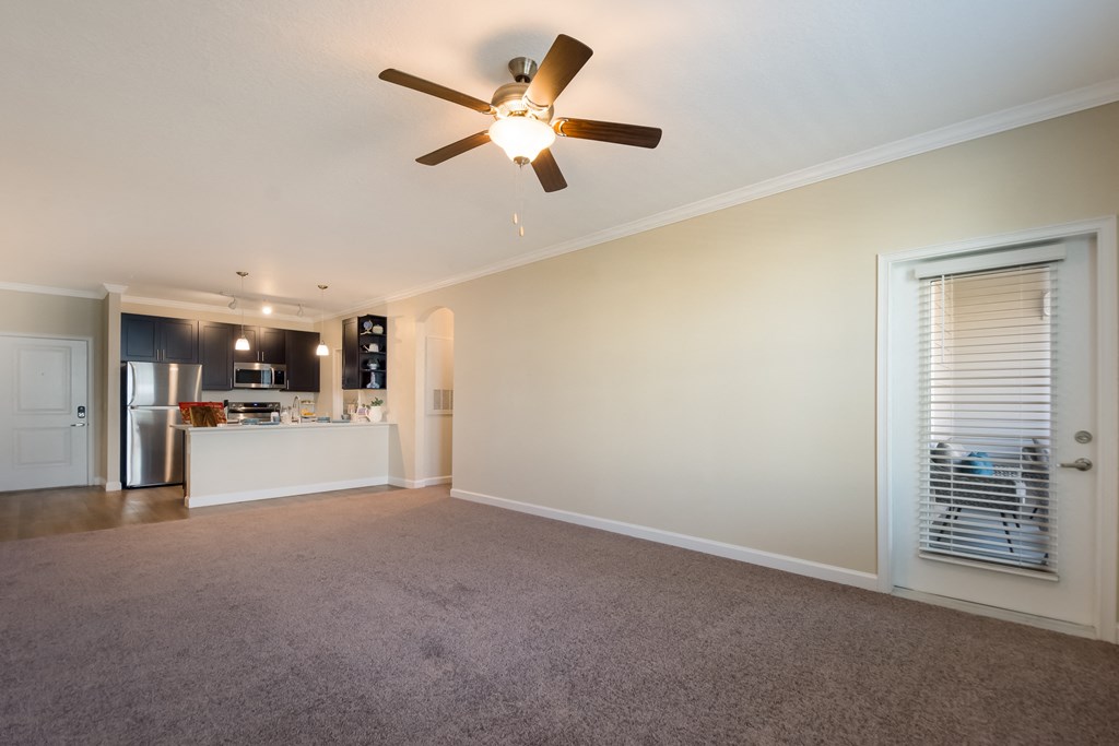 a living room with a ceiling fan and a kitchen in the background  at The Oasis at Manatee River, Bradenton, FL, 34211