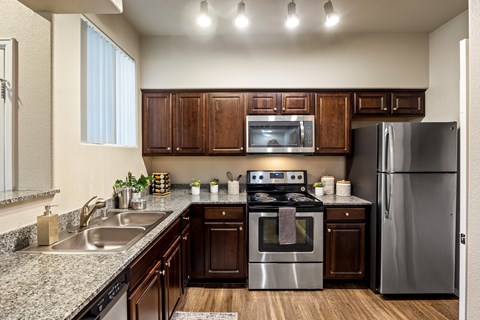 A modern kitchen with dark wood cabinets and stainless steel appliances.