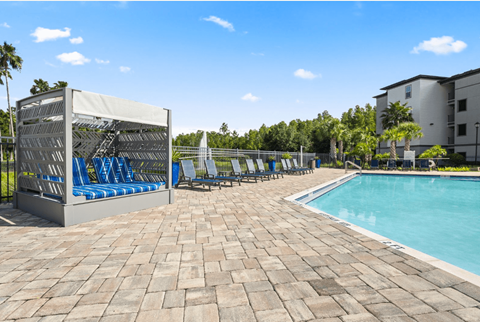 A poolside area with a sunshade, lounge chairs, and a pool.