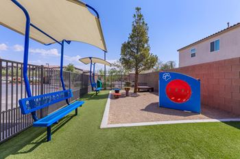 a playground with a blue bench and a playset and umbrella at The Preserve by Picerne, N Las Vegas, NV, 89086