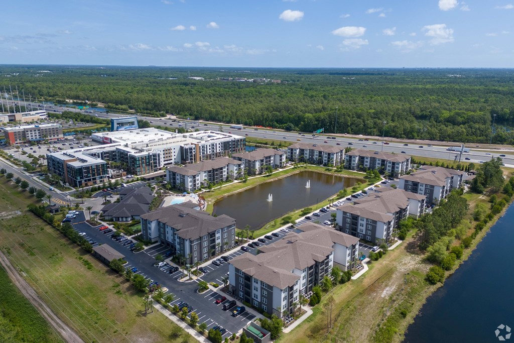A bird's eye view of a residential area with a lake and apartment buildings.