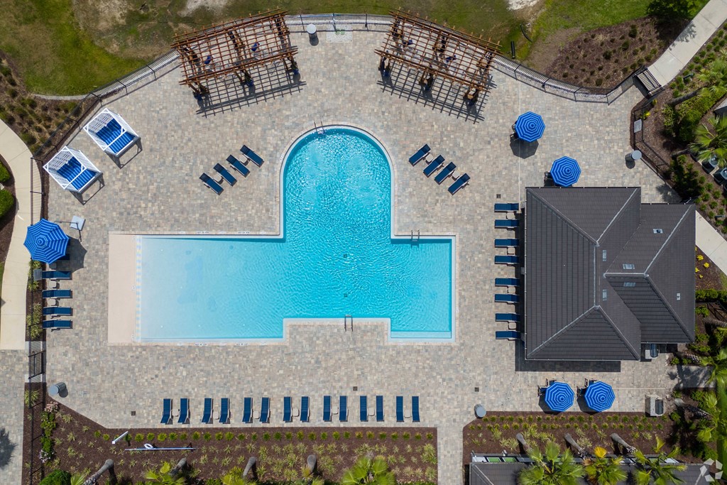 An aerial view of a pool surrounded by lounge chairs and umbrellas.