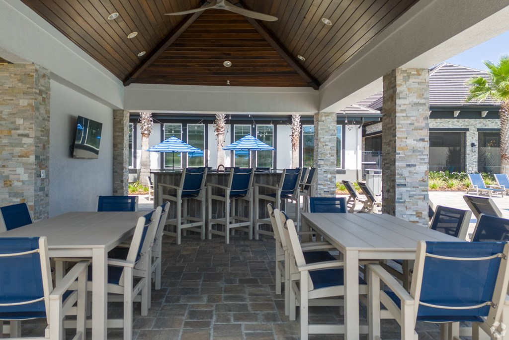 A patio with tables and chairs and umbrellas.