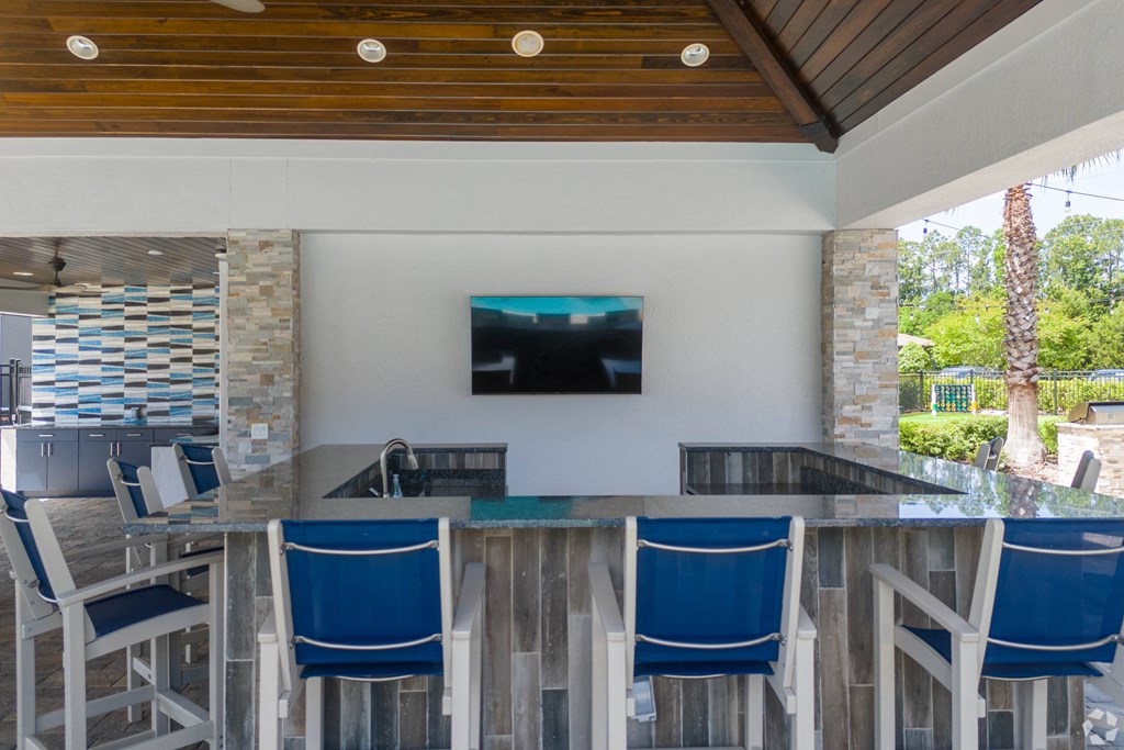 A wooden table with blue chairs and a television on the wall.