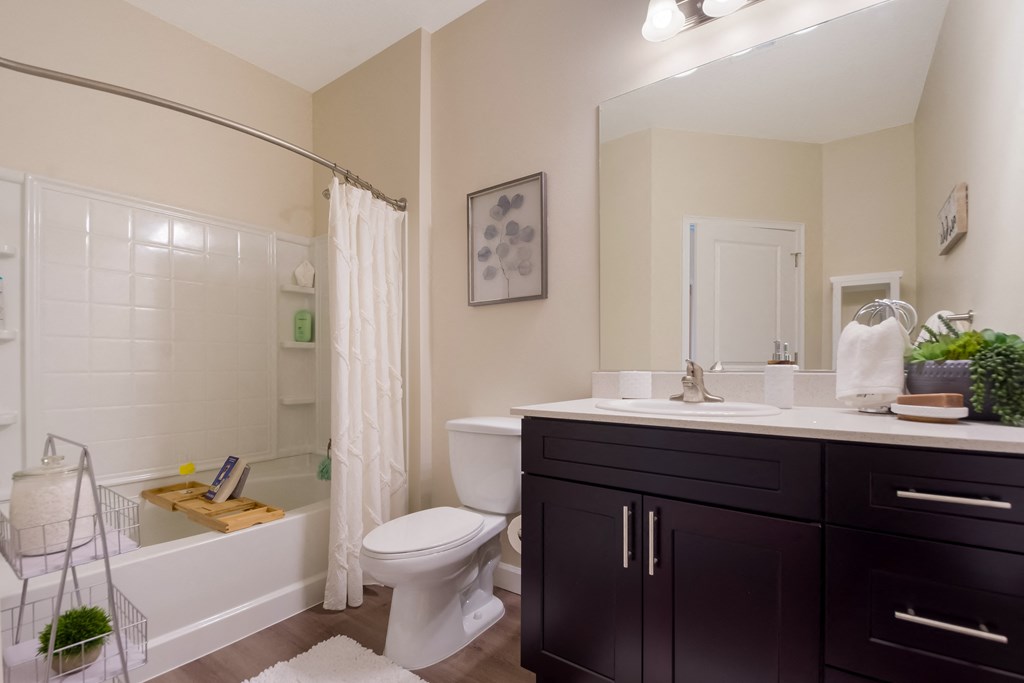 a bathroom with a white toilet next to a bathtub with a shower curtain  at The Oasis at Manatee River, Bradenton