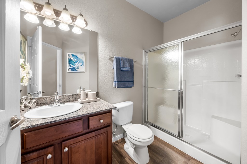 A bathroom with a white toilet, sink, and shower at The Equestrian by Picerne Apartments, Henderson