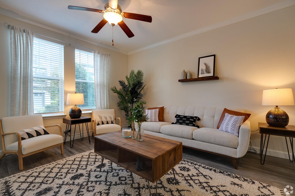 A living room with a white couch, a wooden coffee table, and a ceiling fan.