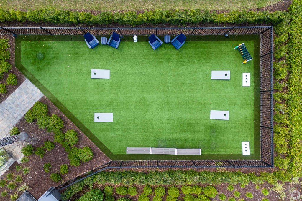 A green lawn with a white fence and blue chairs.