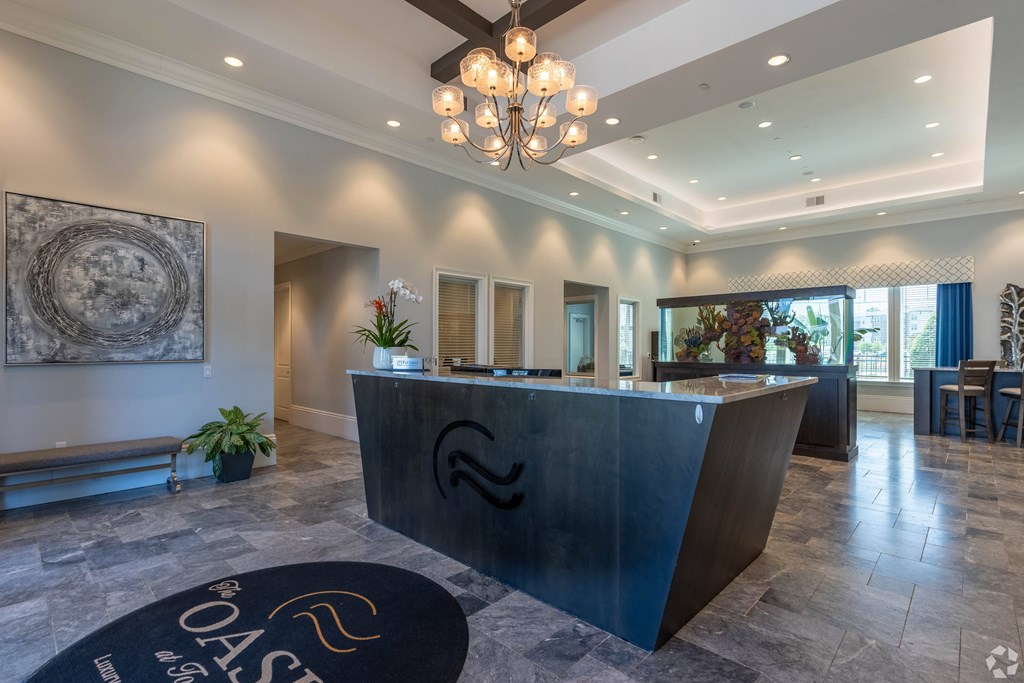 A reception area with a black reception desk and a chandelier hanging from the ceiling.