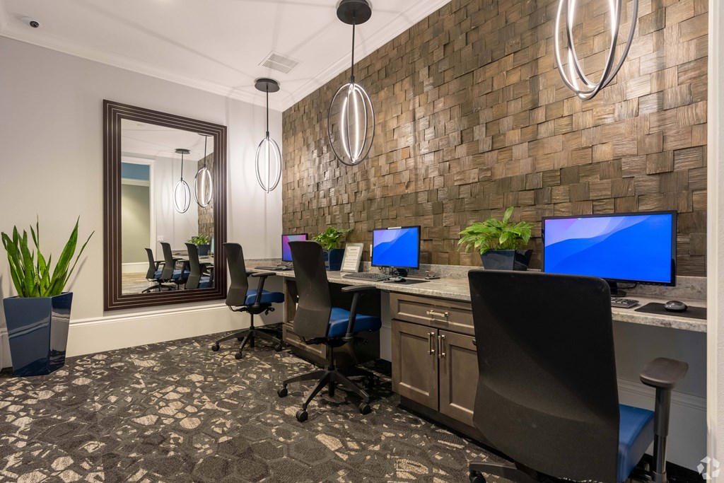 A room with a brick wall and a row of computer monitors.