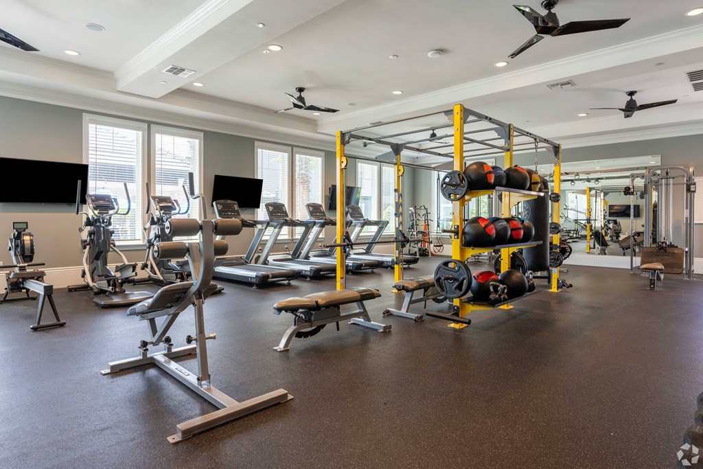 A gym with a variety of equipment including weights and treadmills.
