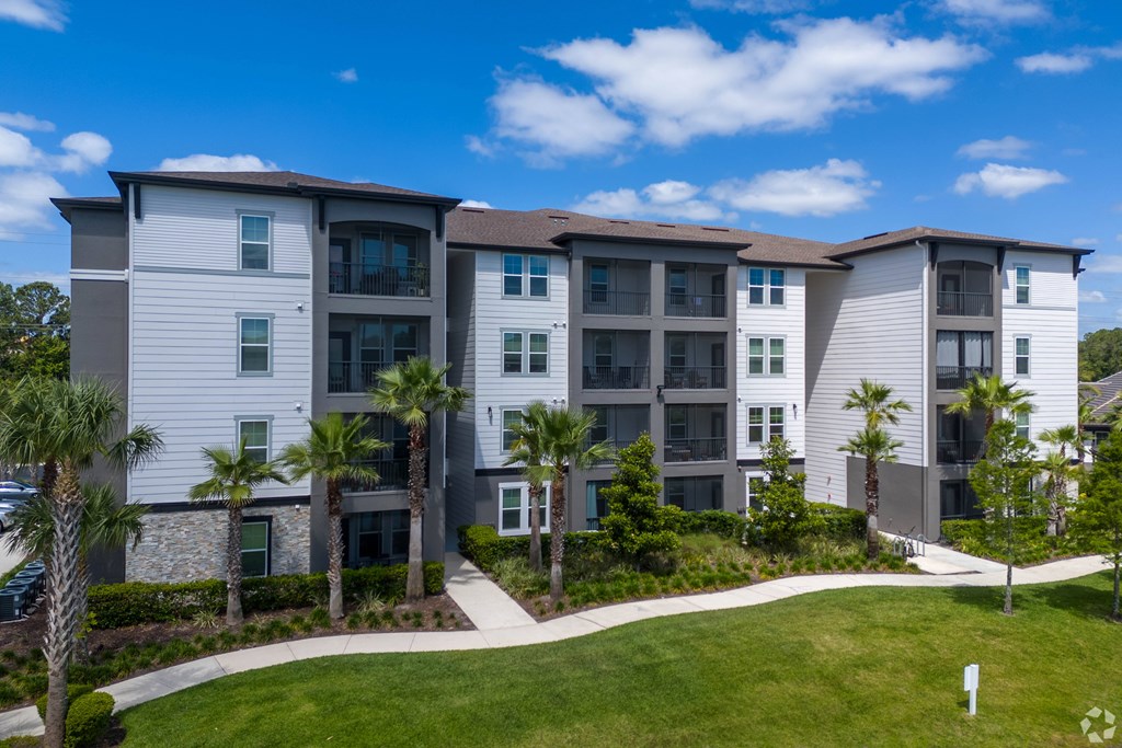 A modern apartment building with a well-manicured lawn in front.
