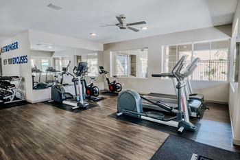 A gym with a variety of exercise equipment including treadmills, elliptical machines, and a stationary bike.