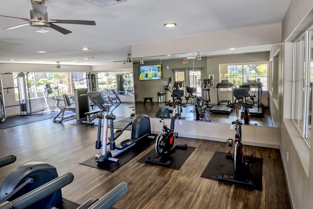 A gym with a variety of exercise equipment including treadmills, stationary bikes, and weight machines.