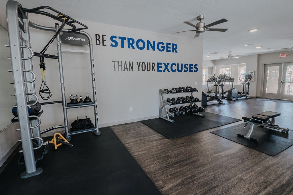 A gym with a sign that says Be Stronger Than Your Excuses