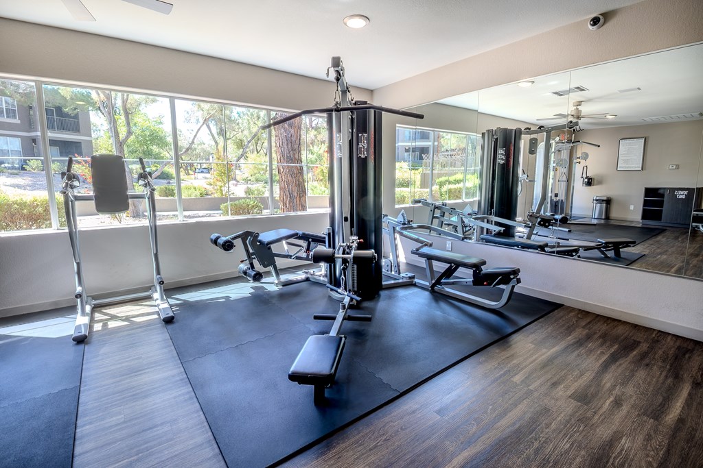 A gym with a variety of equipment including a squat rack, bench press, and a mirror.