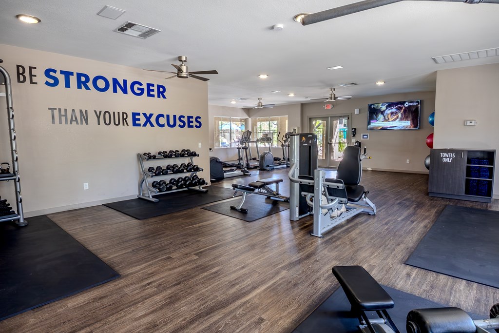 Large gym room with plank flooring, free weights, and aerobic machines