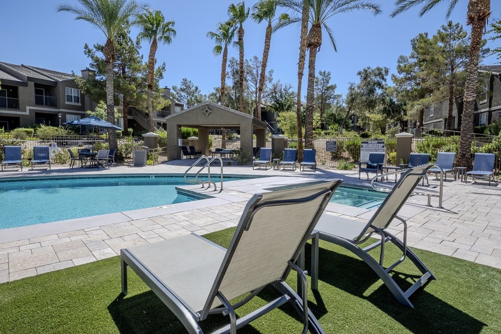 A poolside area with lounge chairs and palm trees.