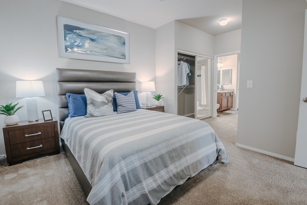 A bedroom with a large bed and a painting on the wall.