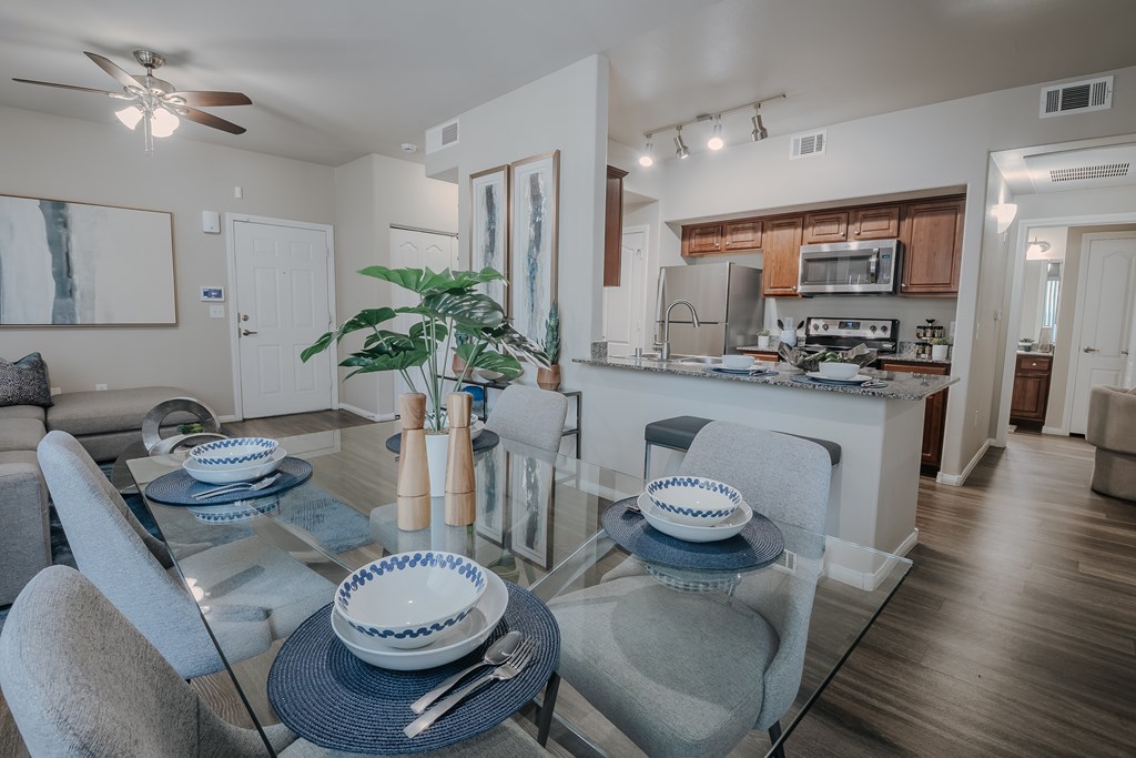 A modern dining room with a glass table and grey chairs.