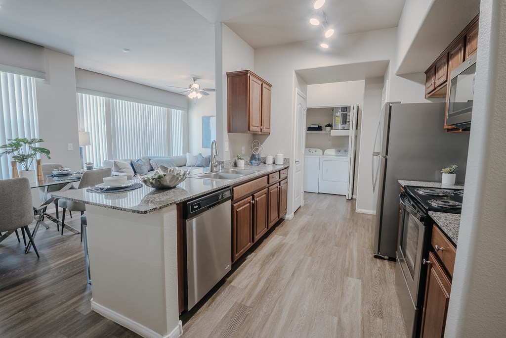 A modern kitchen with wooden floors and stainless steel appliances.