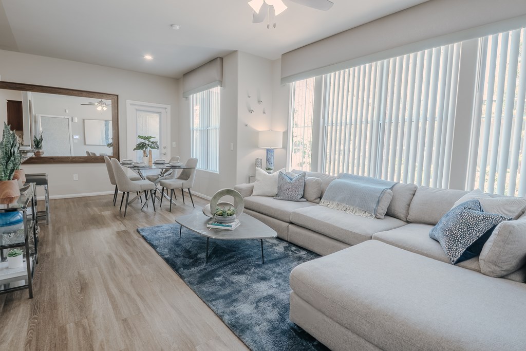 A living room with a white sofa, a coffee table, and a dining table with chairs.