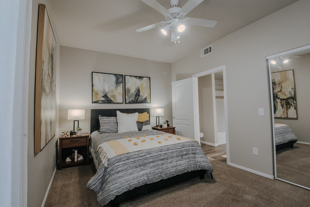 A bedroom with a large bed and a ceiling fan.