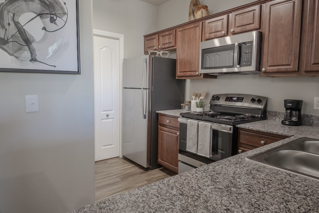 A kitchen with a refrigerator, microwave, oven, and sink.