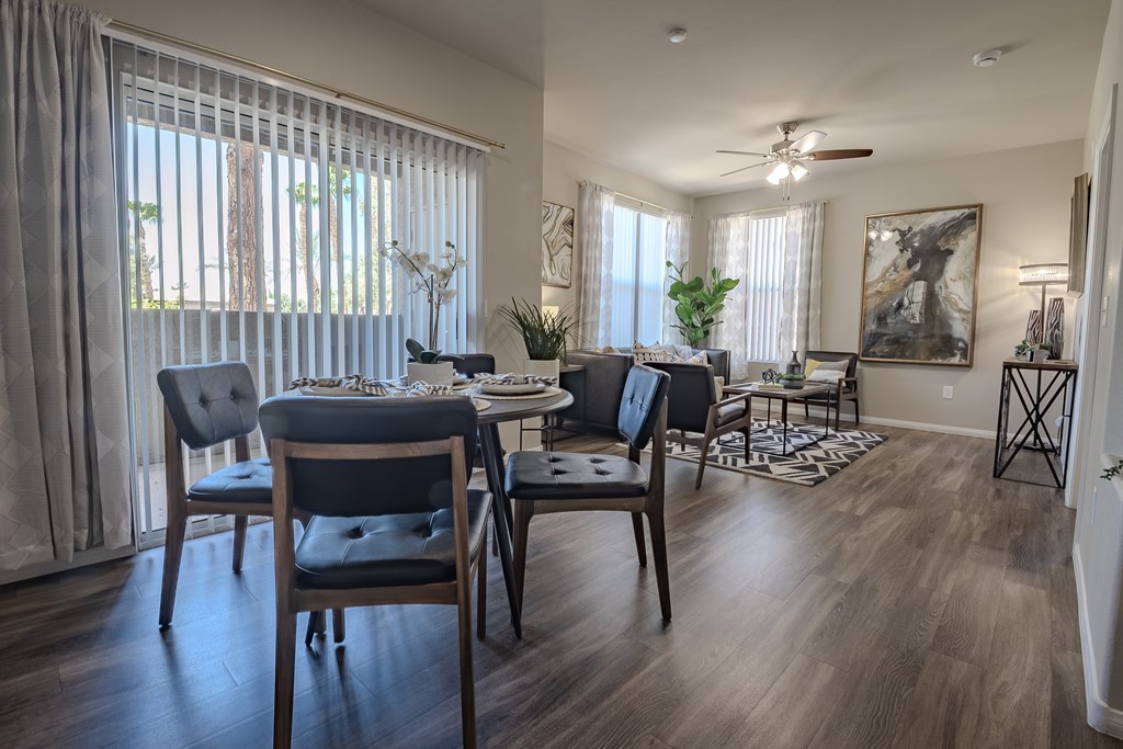 A dining room with a table set for four and a ceiling fan.