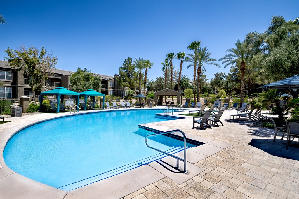 A large swimming pool surrounded by palm trees and sun loungers.
