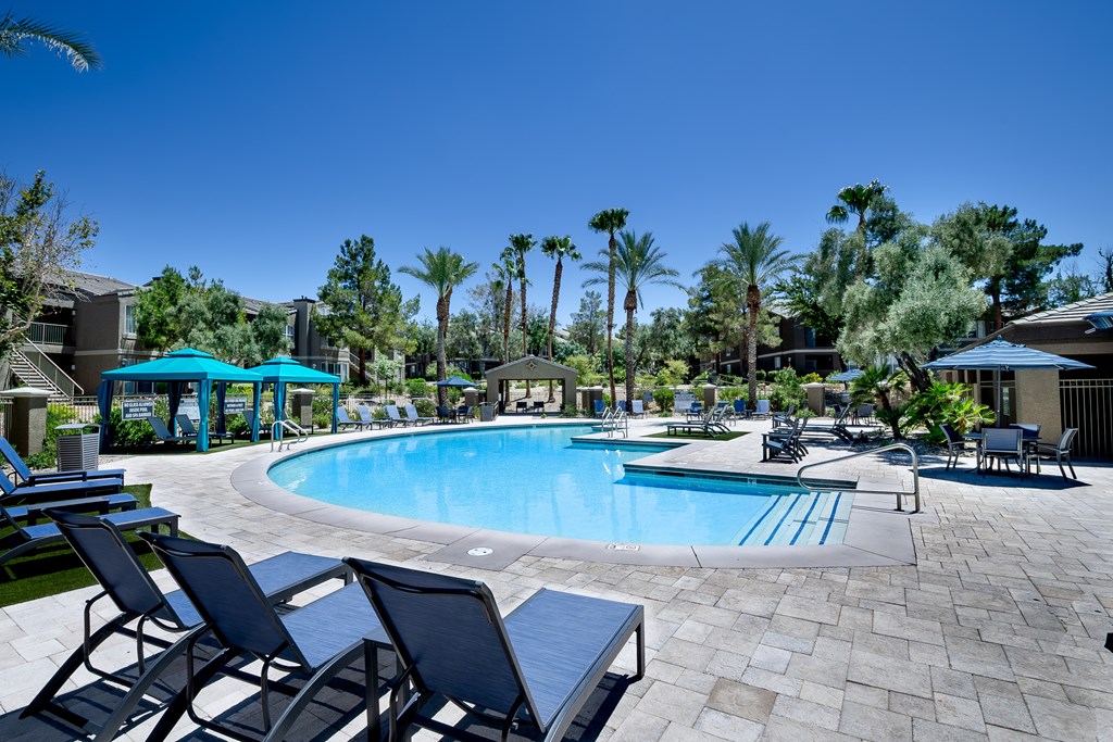 A pool surrounded by chairs and palm trees.