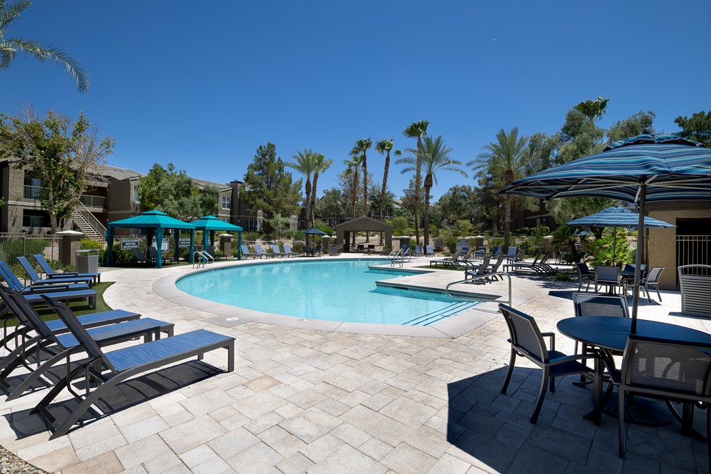 A pool area with chairs and umbrellas.