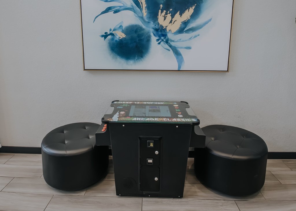 Clubhouse game table and two large black ottomons.