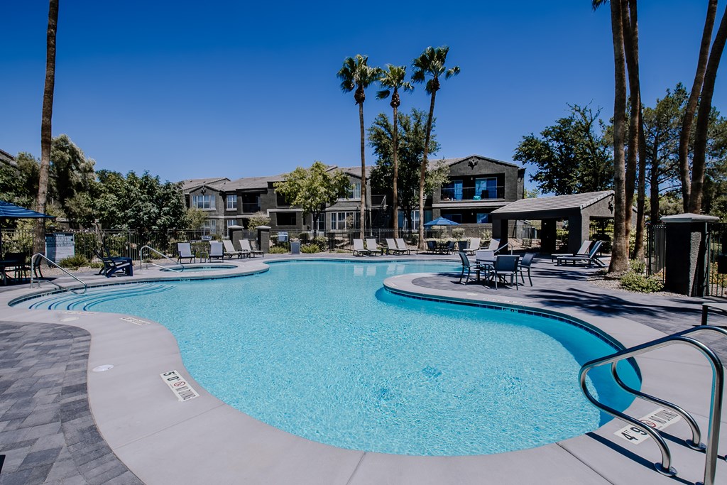 A large swimming pool surrounded by palm trees and lounge chairs.