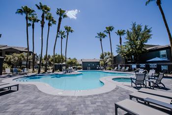 A pool surrounded by palm trees and lounge chairs.