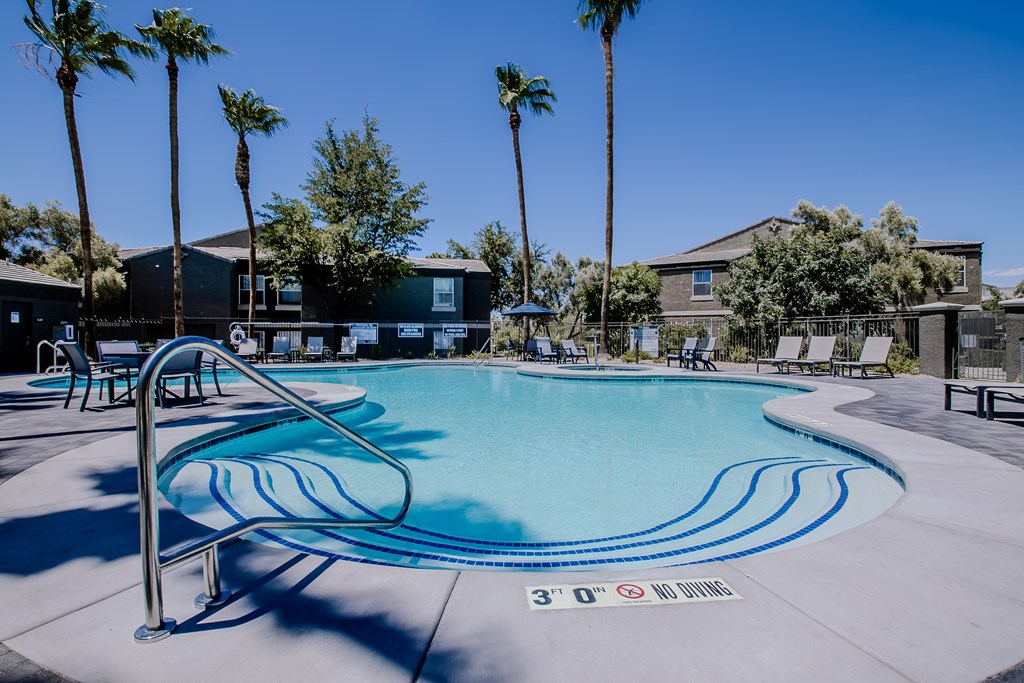 A swimming pool surrounded by palm trees and lounge chairs.